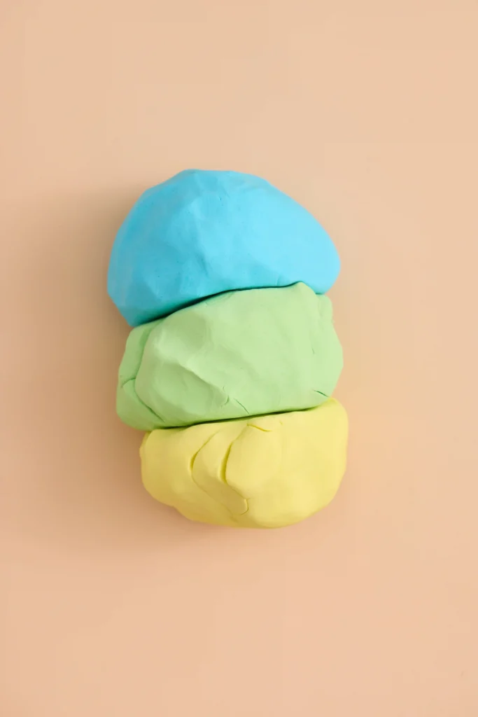 cloud dough in blue yellow and green on a peach background