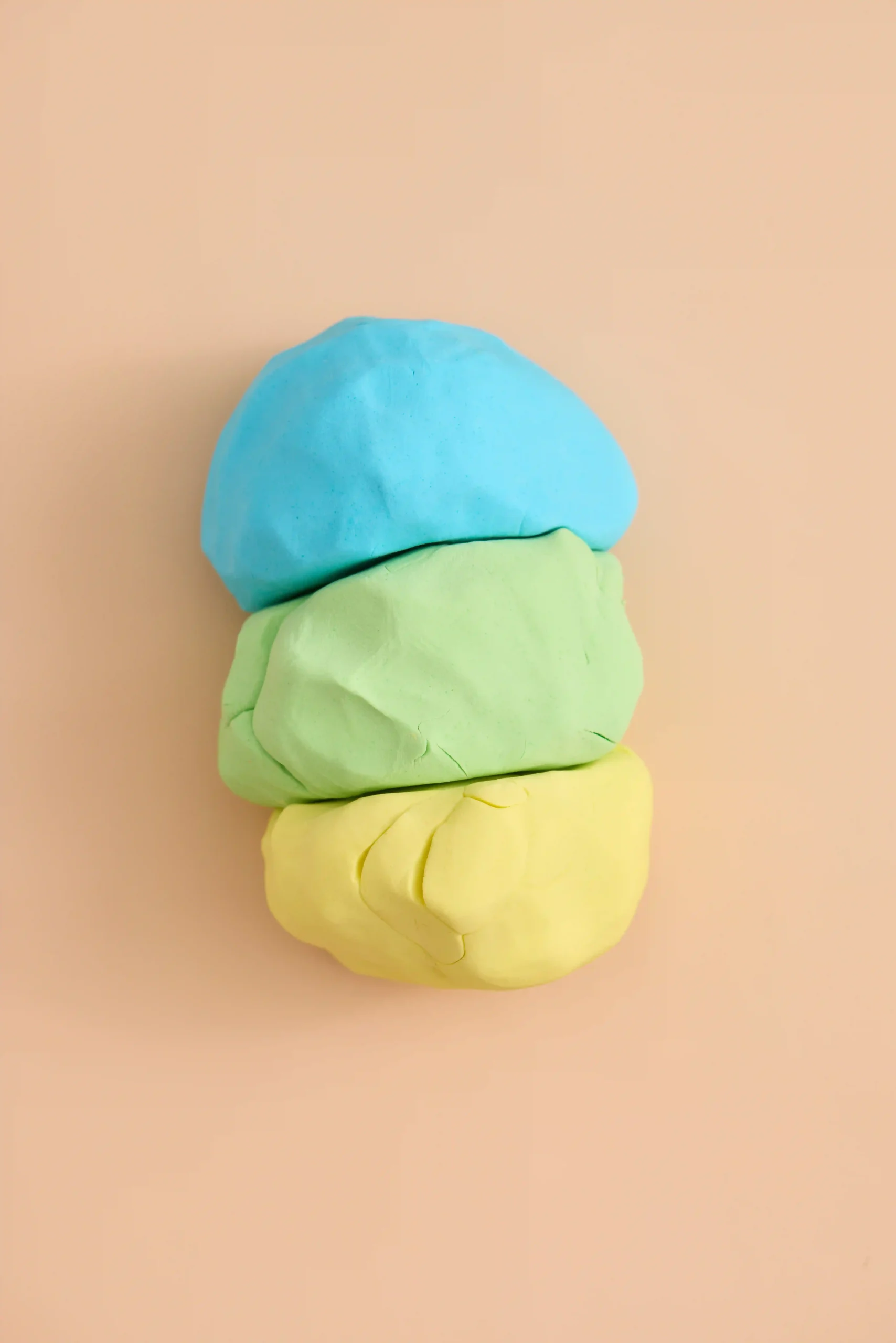 cloud dough in blue yellow and green on a peach background