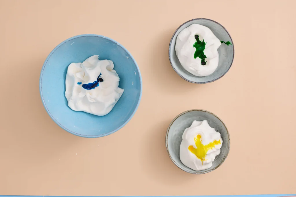 cloud dough separated into bowl with food coloring in each bowl