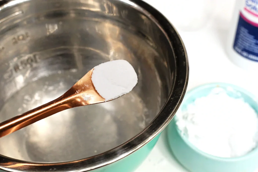 baking soda being added to a mixing bowl of water and glue