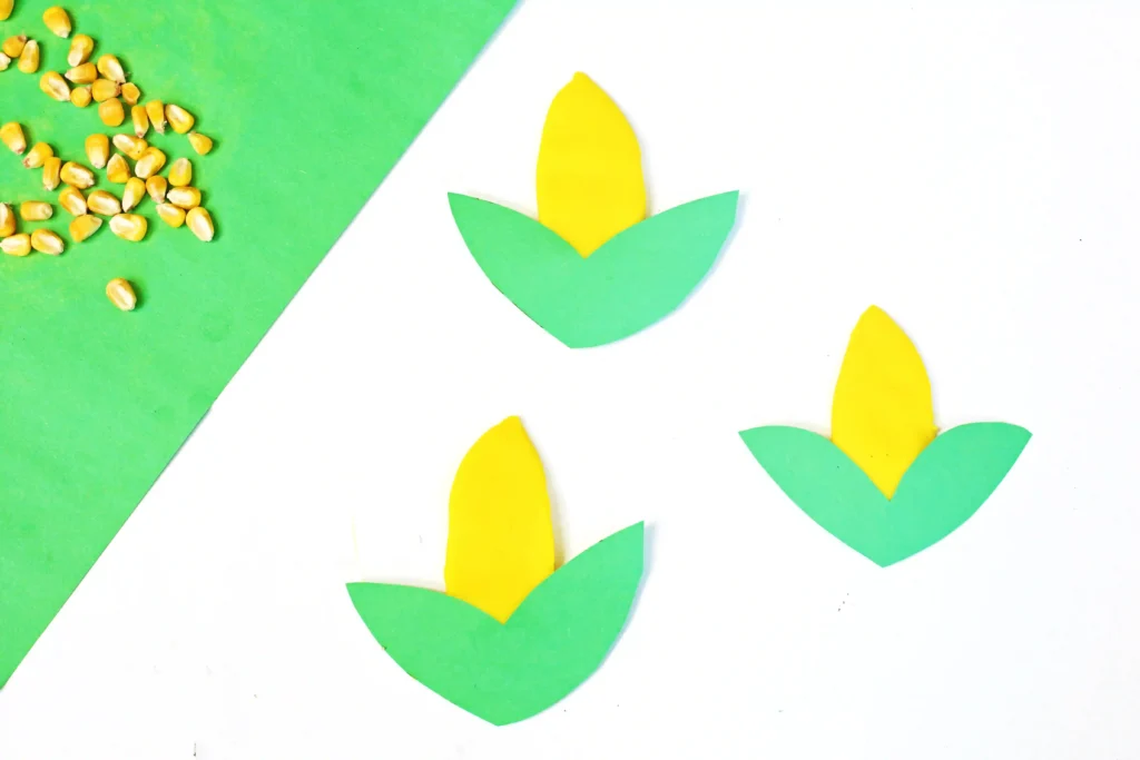 green construction paper corn husks on top of yellow playdough to look like corn