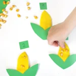 a Corn Playdough Math Activity; a kid is pressing corn kernels into playdough