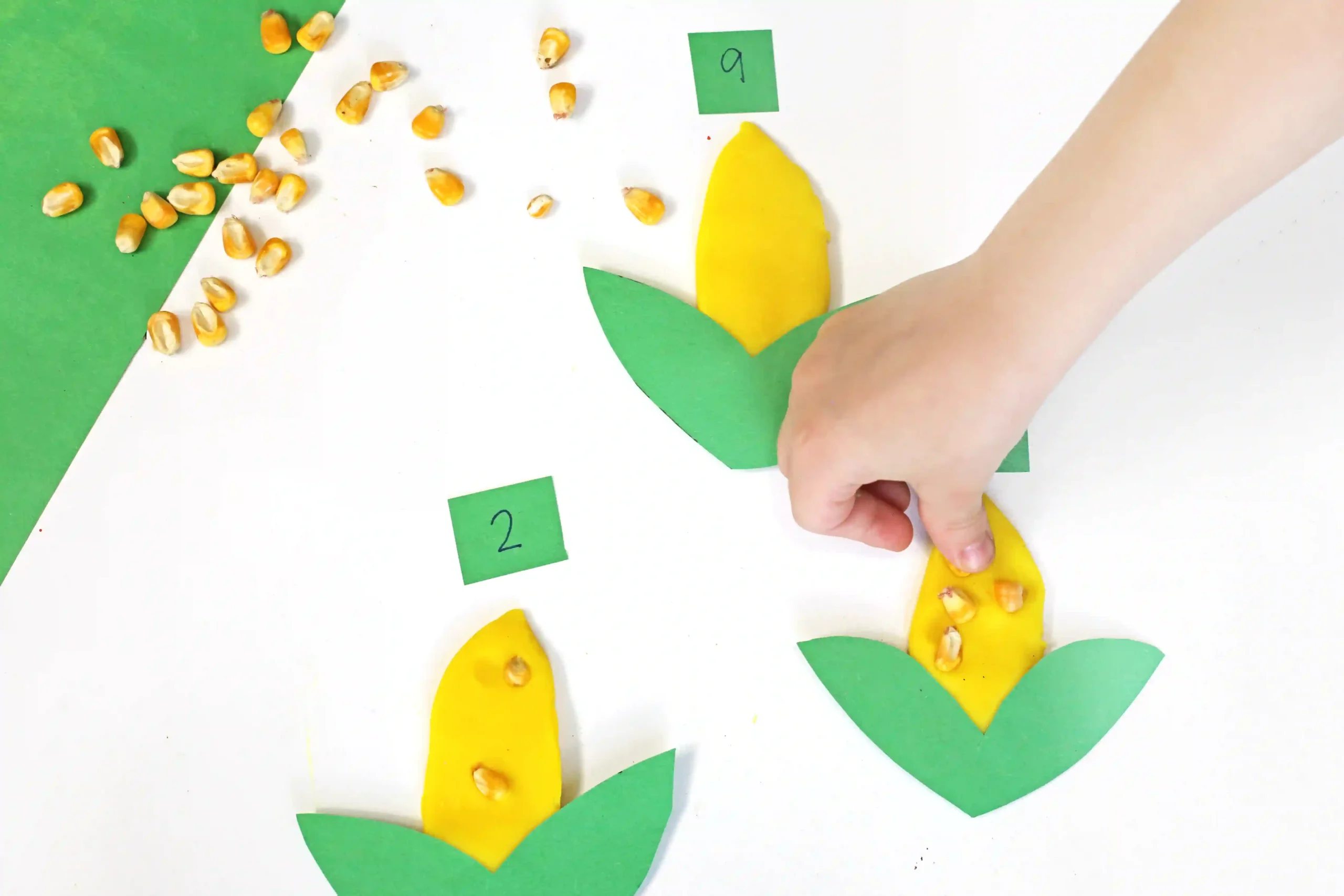 a Corn Playdough Math Activity; a kid is pressing corn kernels into playdough