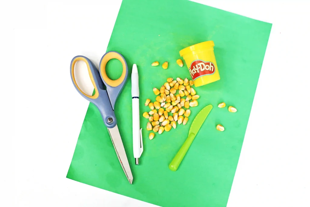 supplies for the fall math activity- green construction paper, yellow playdough, corn kernels, scissors, and a marker
