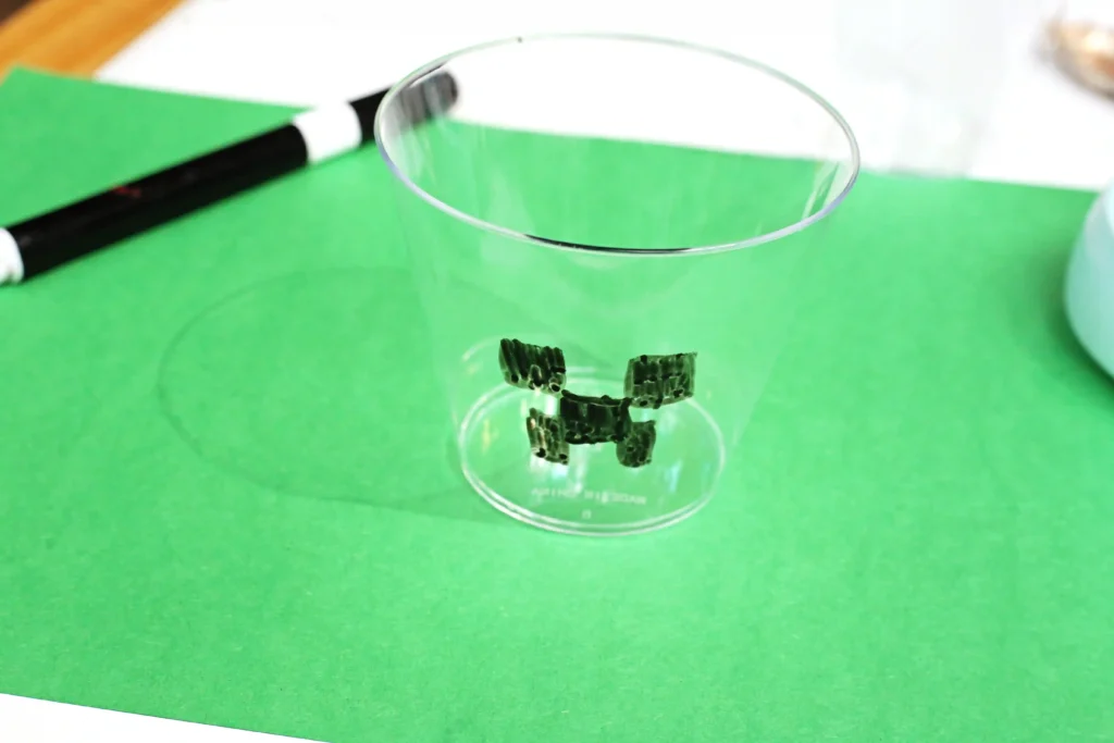 a clear plastic cup with a minecraft creeper face draw on 