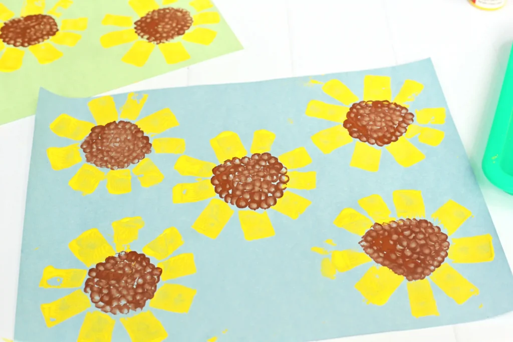 a toilet paper roll sunflower craft that is blue construction paper with sunflowers painted on