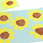 a toilet paper roll sunflower craft that is blue construction paper with sunflowers painted on