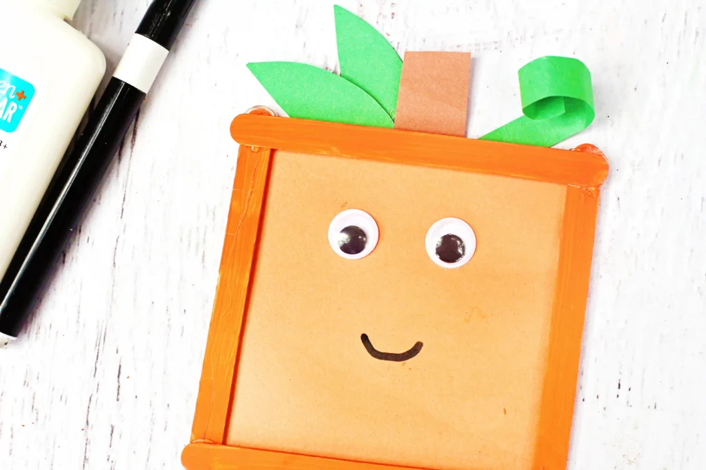Spookley the Square Pumpkin Craft that uses orange popsicle sticks, green and orange construction paper, and googly eyes to make a square pumpkin