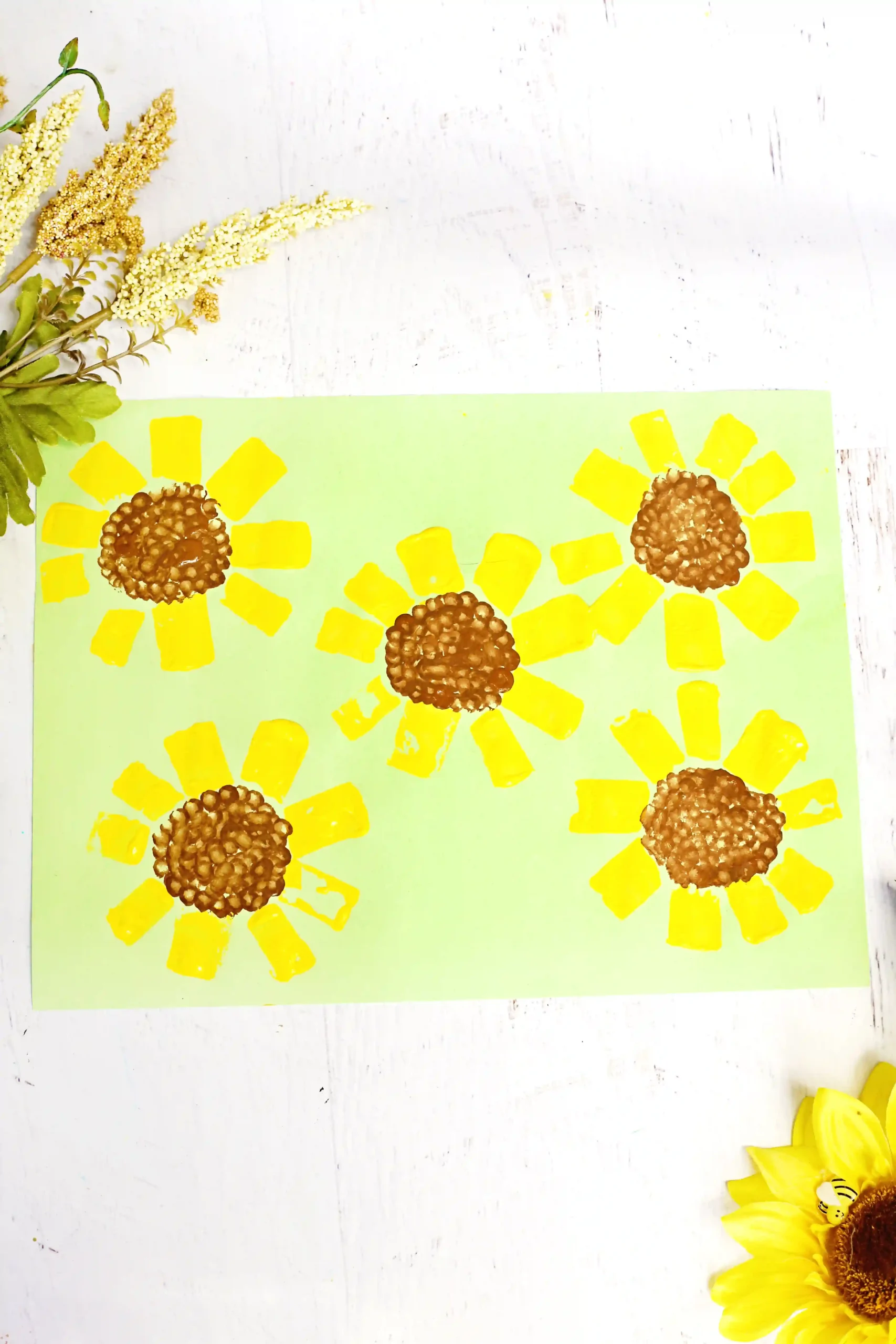 a toilet paper roll sunflower craft that is green construction paper with sunflowers painted on