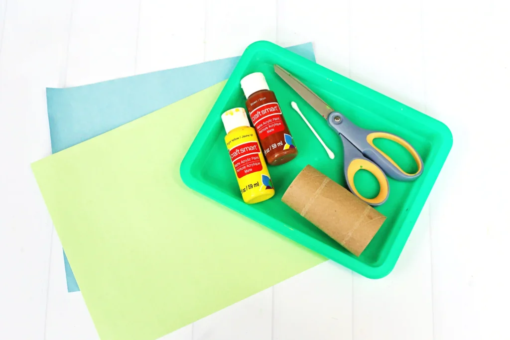 supplies for the fall crafts for kids: blue and green construction paper, yellow and brown paint, cotton swab, toilet paper roll, a tray and scissors