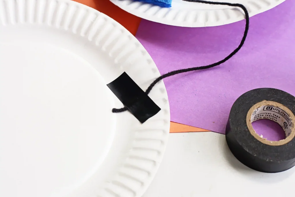 a piece of yarn taped to a paper plate