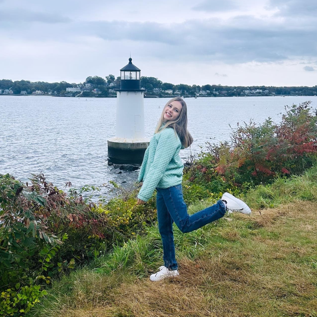 a girl standing in front of a light house