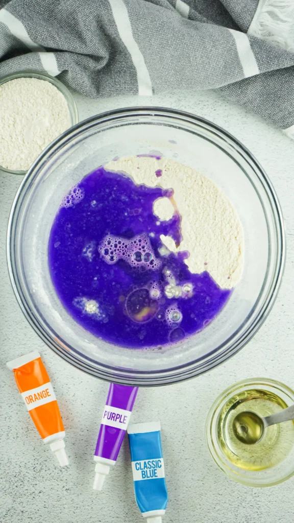 purple food coloring added to a bowl of salt, flour, and oil