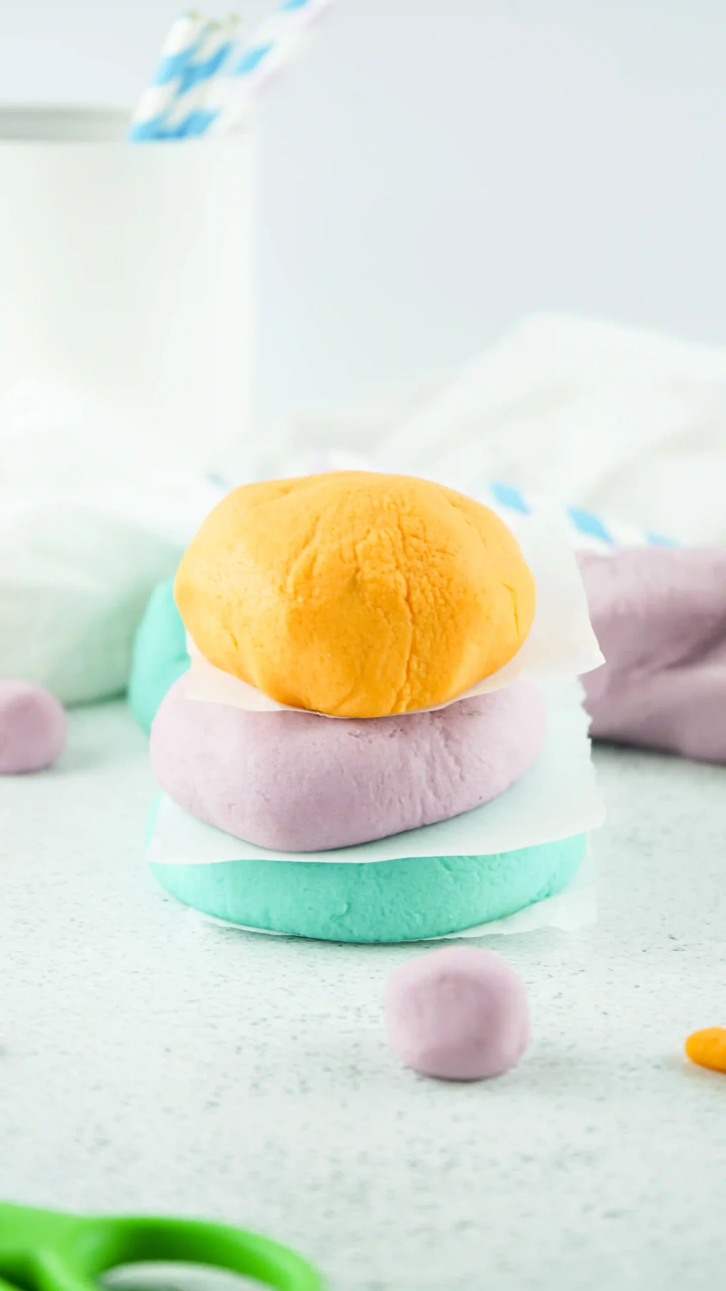 homemade playdough in orange, purple, and blue stacked on top of one another