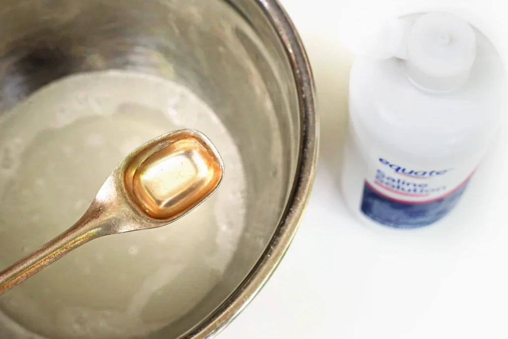 contact solution being added to a bowl of glue, water, and baking soda