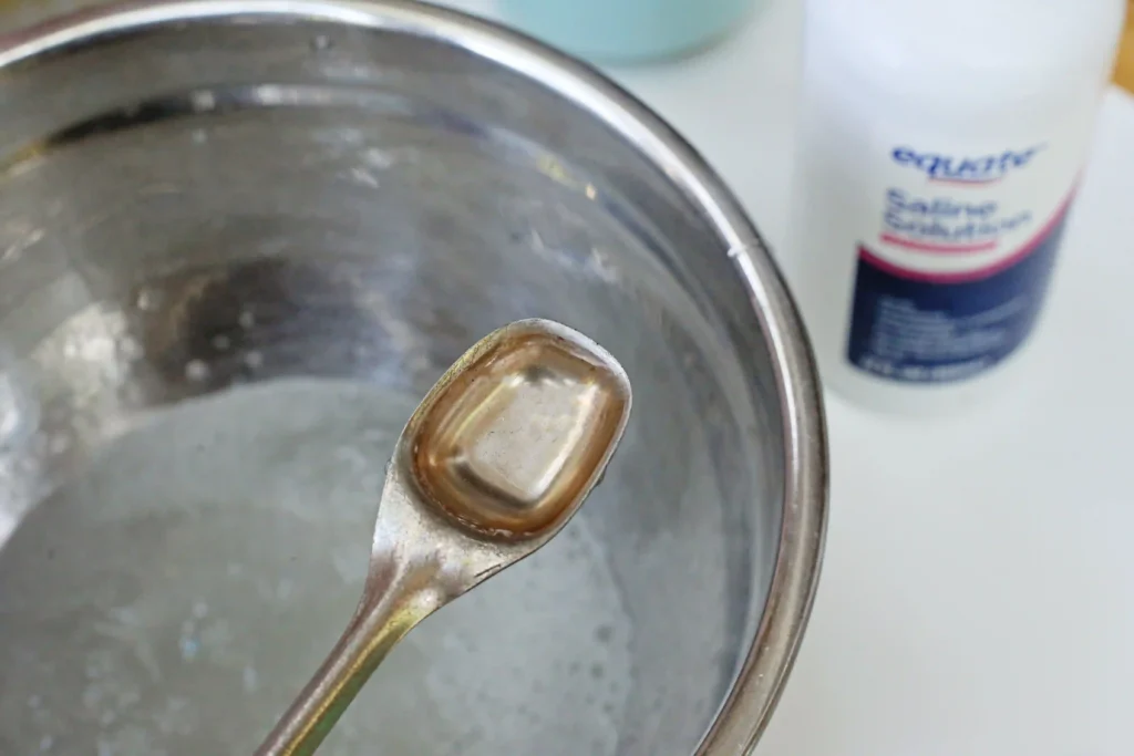 contact solution being added to a bowl of baking soda, water, and glue for these LEGO activities