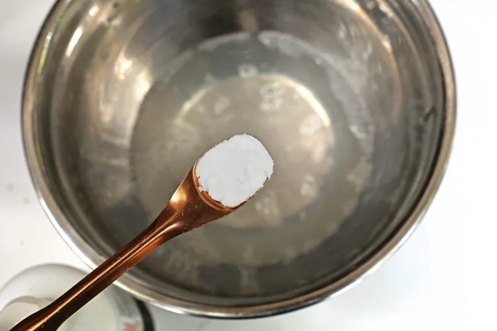 baking soda being added to a bowl of glue and water