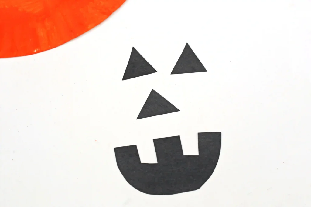 a jack o lantern face cut out of black construction paper