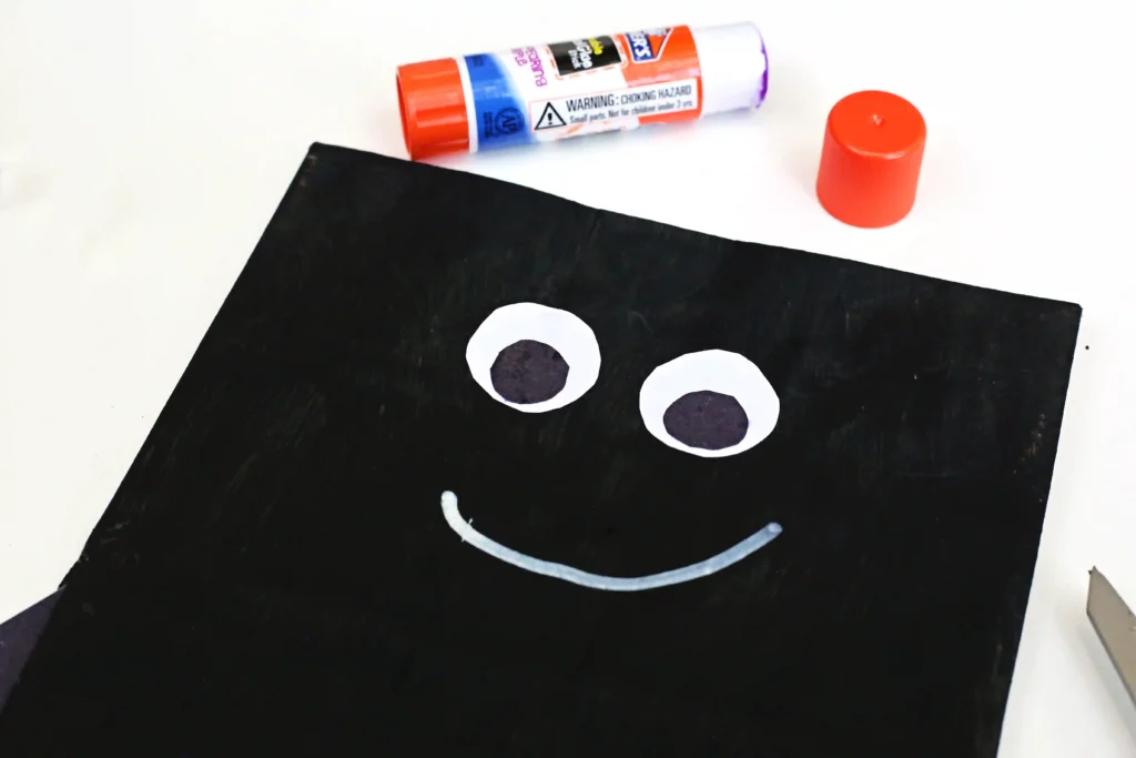 a paper bag painted black with construction paper eyes and a white smile