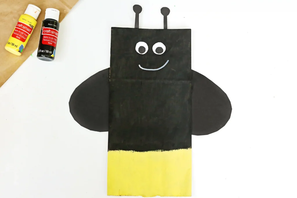 a Firefly Paper Bag Craft of a paper plag painted black and yellow and decorated to look like a firefly