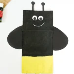 a Firefly Paper Bag Craft of a paper plag painted black and yellow and decorated to look like a firefly