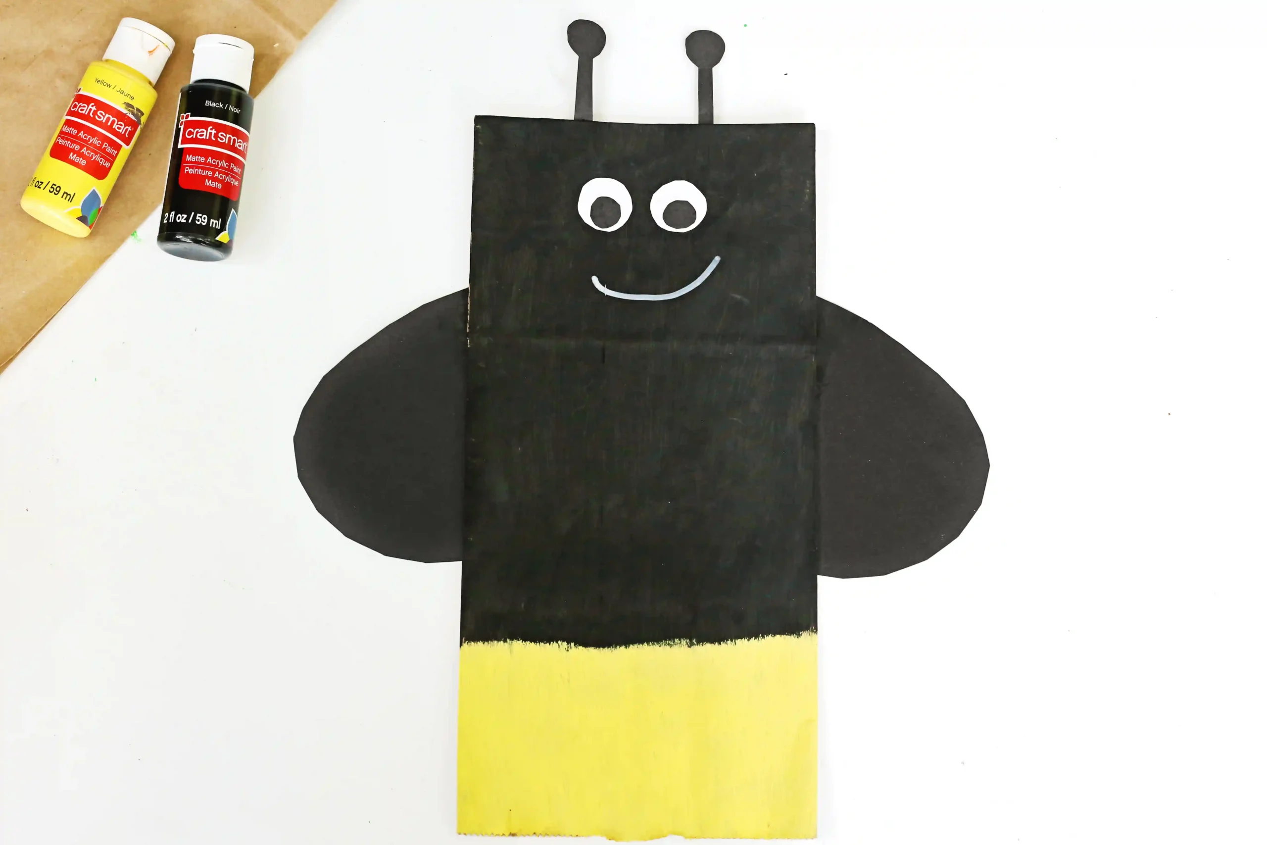a Firefly Paper Bag Craft of a paper plag painted black and yellow and decorated to look like a firefly