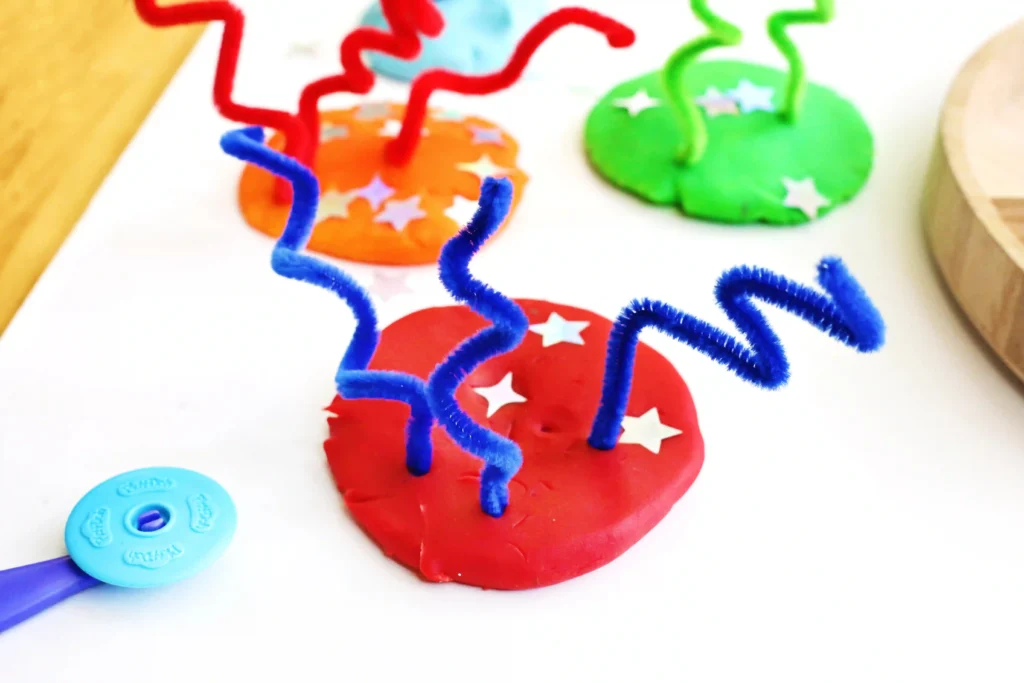 a Fireworks Playdough Tray that uses playdough, pipe cleaners, and foam stars to look like fireworks