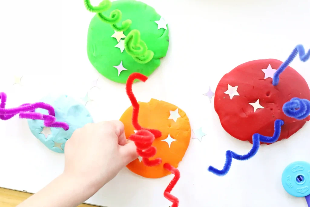 a Fireworks Playdough Tray that uses playdough, pipe cleaners, and foam stars to look like fireworks
