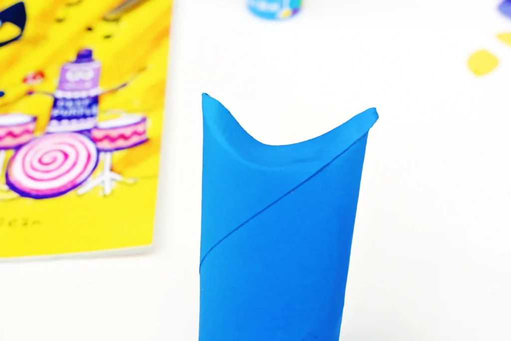 a toilet paper roll painted blue with the top folded down to look like ears
