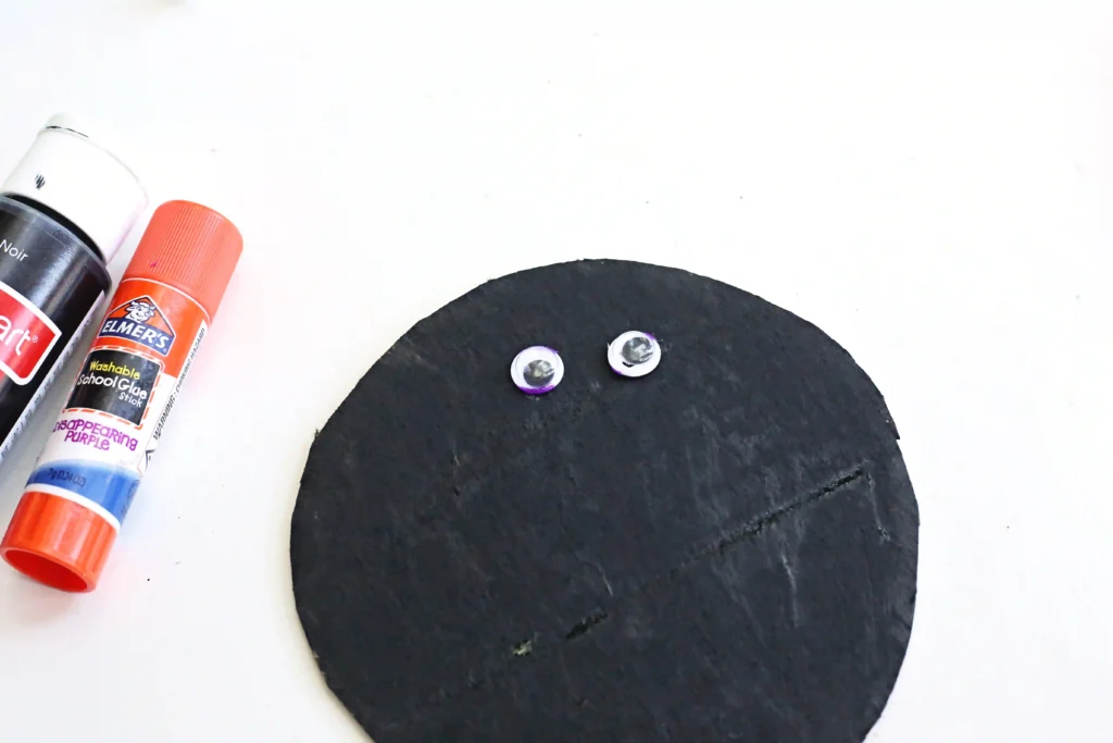 googly eyes glued on a piece of cardboard that's been painted black