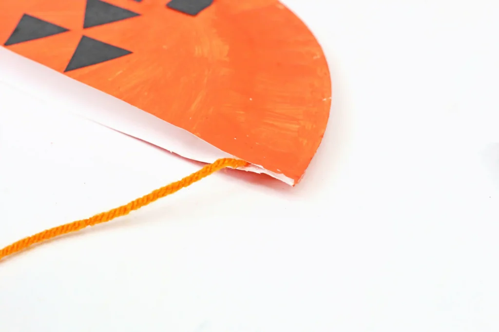orange string glued to a papee plate bag