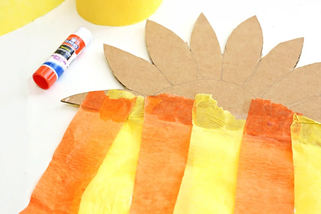 yellow and orange streamers glued onto the back of a sunflower cut out of cardboard