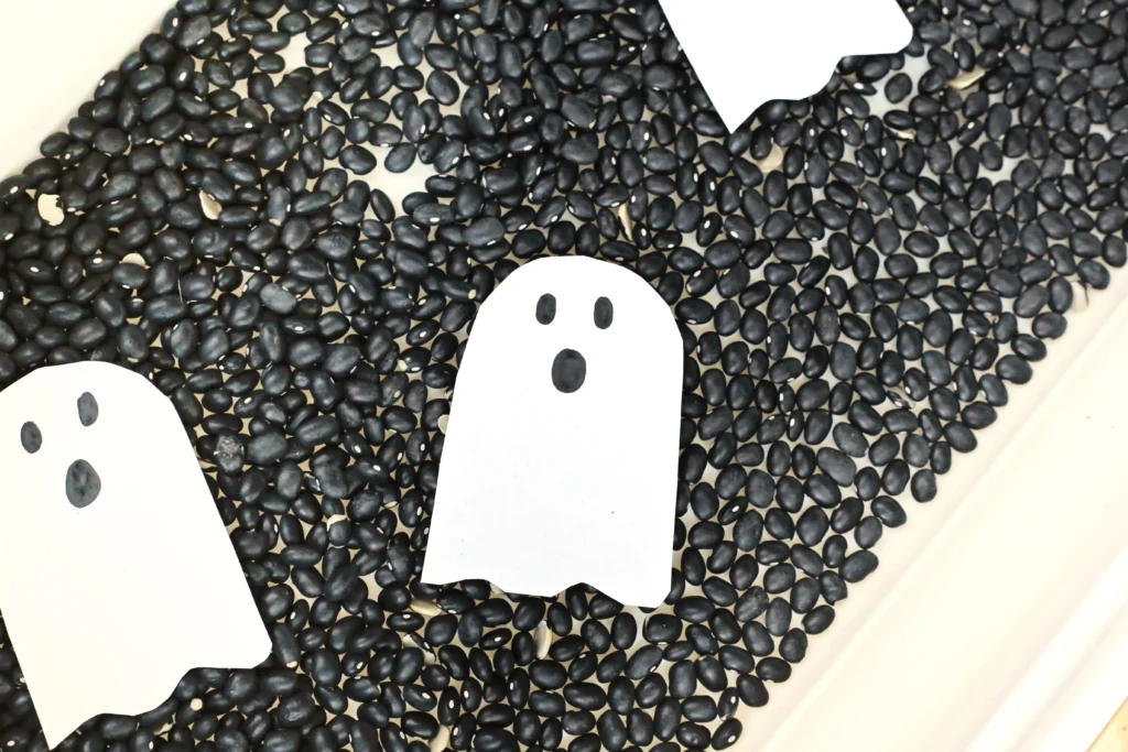paper ghosts in a bin with black beans