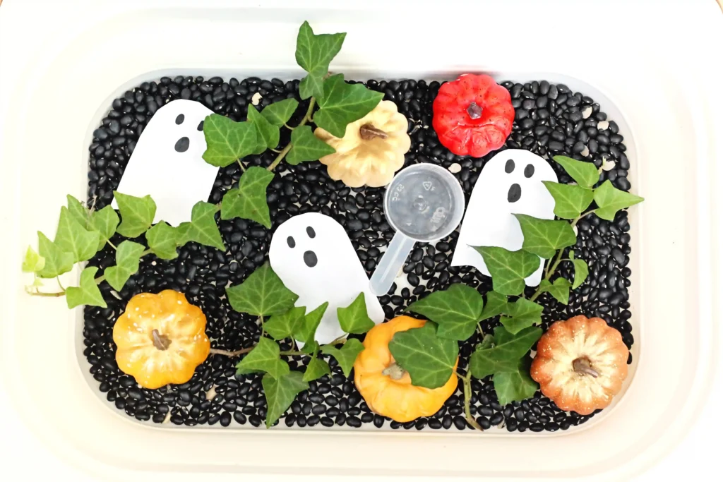 a Haunted Pumpkin Patch Sensory Bin that has black beans, ghosts, and pumpkins