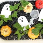 a Haunted Pumpkin Patch Sensory Bin that has black beans, ghosts, and pumpkins