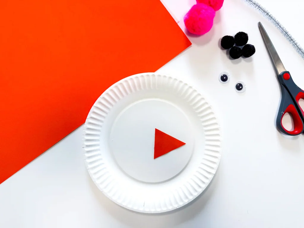 a paper plate with an orange triangular glued in the middle