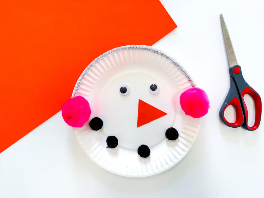 a paper plate decorated to look like a snowman with earmuffs