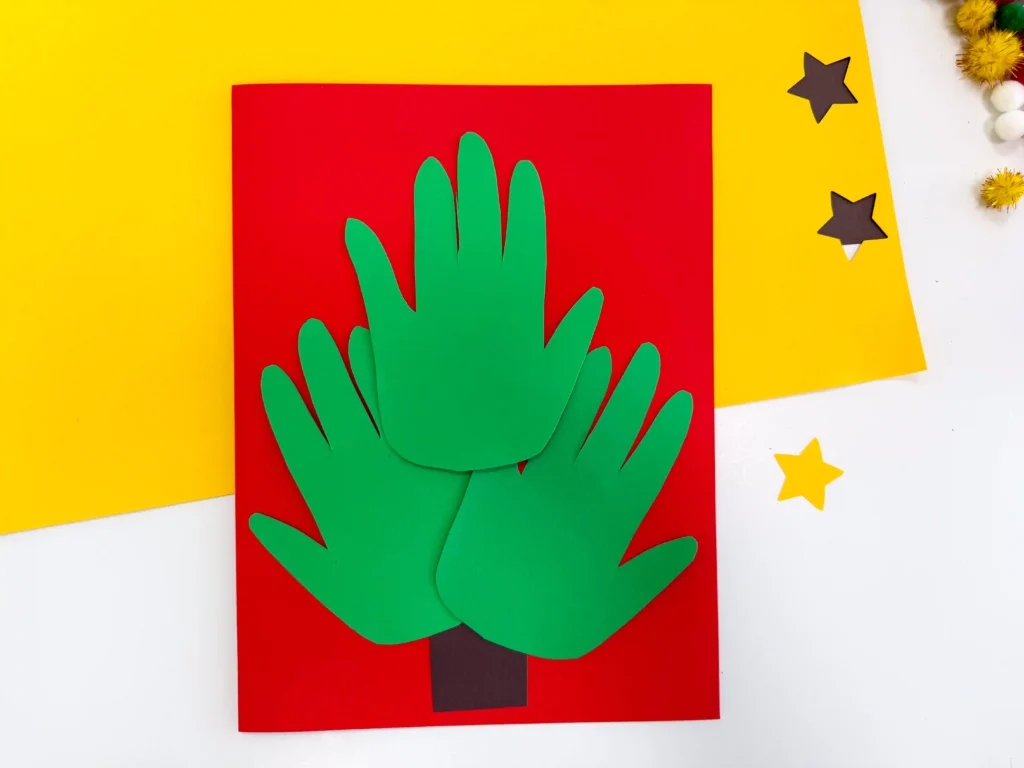 red construction paper with a brown square and green handprints