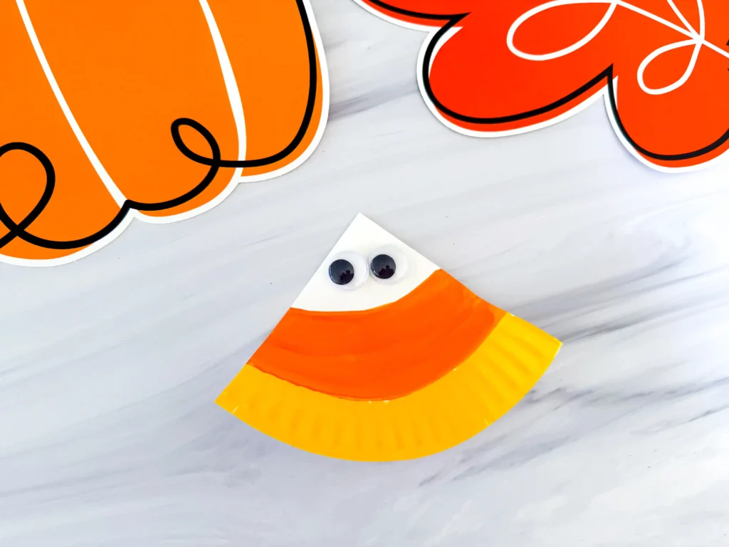 a paper plate painted to look like a candy corn with googly eyes