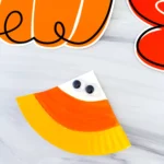 a paper plate painted to look like a candy corn with googly eyes