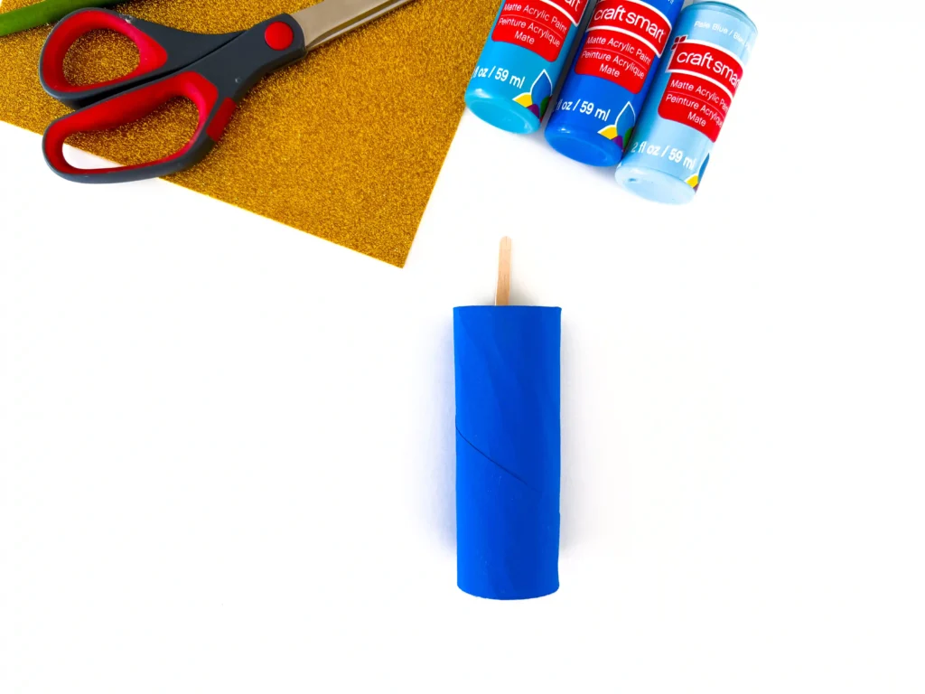 a toilet paper roll painted blue with a popsicle stick sticking out