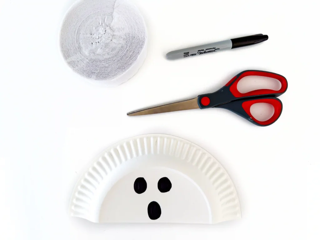 a paper plate cut in half with a ghost face drawn on