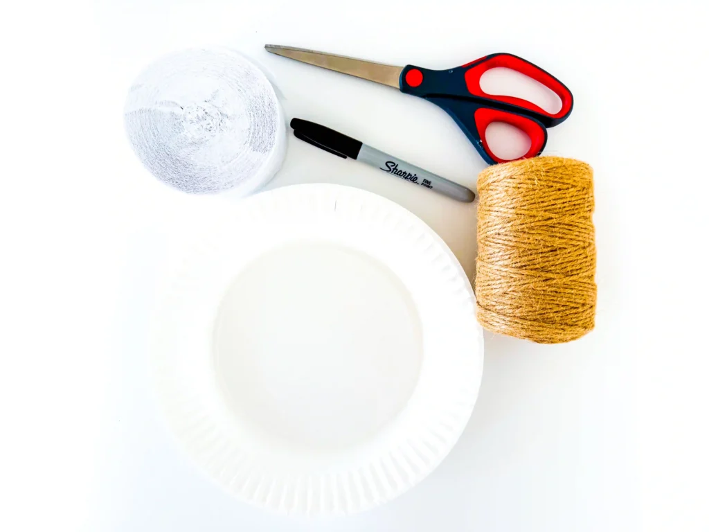 supplies for the ghost paper plate craft: white streamer, paper plate, black marker, scissors, and twine