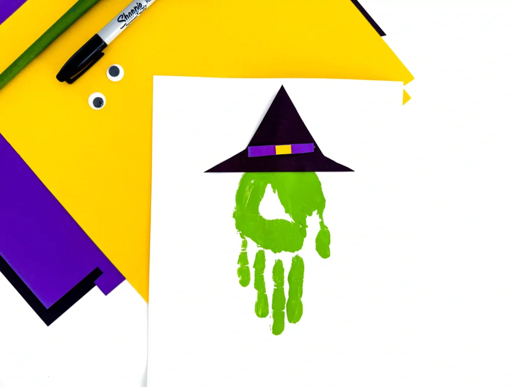 a green handprint with a witch hat glued on