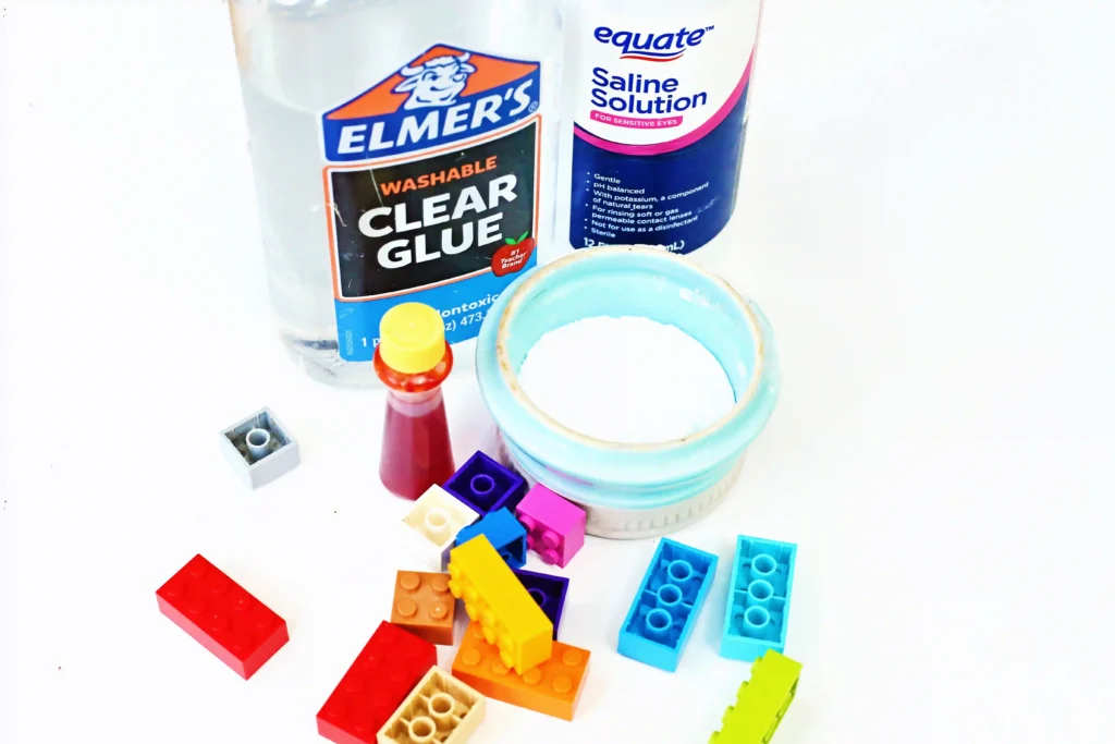 ingredients for the LEGO slime: clear glue, saline solution, baking soda, food coloring, and legos