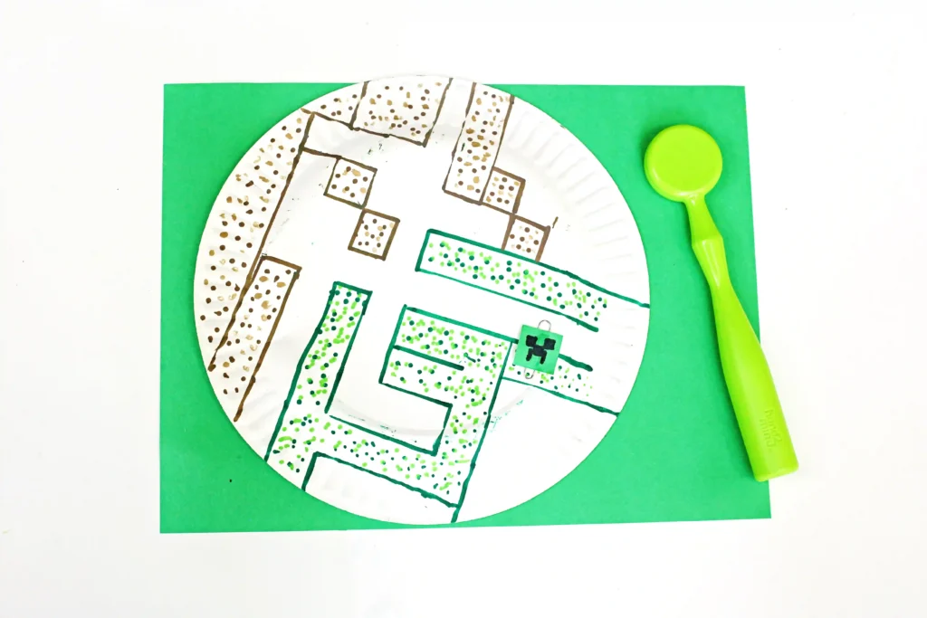 a paper plate with a maze drawn on it next to a magnet