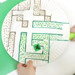 a paper plate with a maze drawn on it next to a magnet