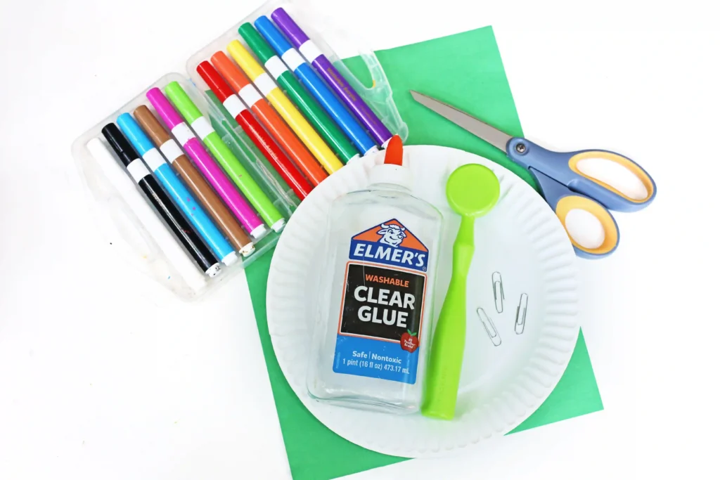 supplies for the magnet paper plate mazes - a paper plate, a magnet wand, glue, construction paper, scissors, markers, and a paper clip