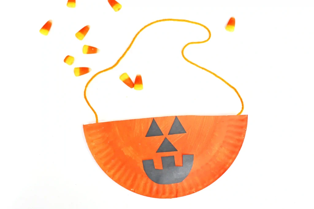 a Paper Plate Jack O Lantern Bag that is a paper plate painted orange with a jack o lantern face