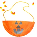 a Paper Plate Jack O Lantern Bag that is a paper plate painted orange with a jack o lantern face